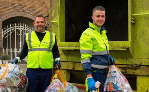 Twee afvalhelden met PMD zakken achter de vrachtwagen