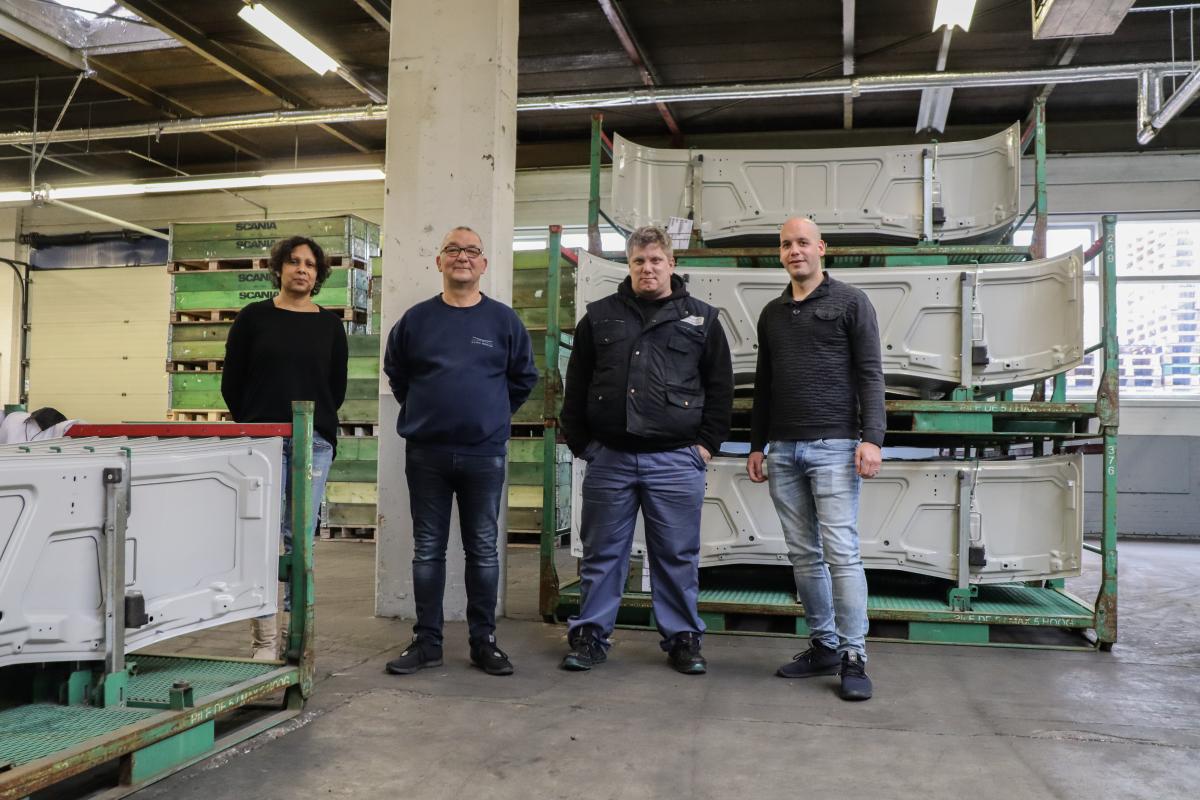 Medewerker Ruben met jobcoaches Aroona en Louis en teamleider Petro van Alro poseren op de werkvloer