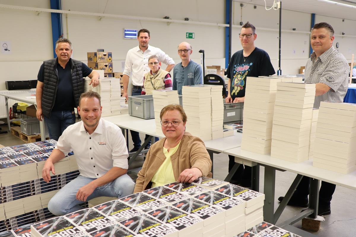 Mike, Roger, Roger, Brigitte en Marco poseren met medewerkers van Beschut 2.0 tussen de boeken op de werkvloer