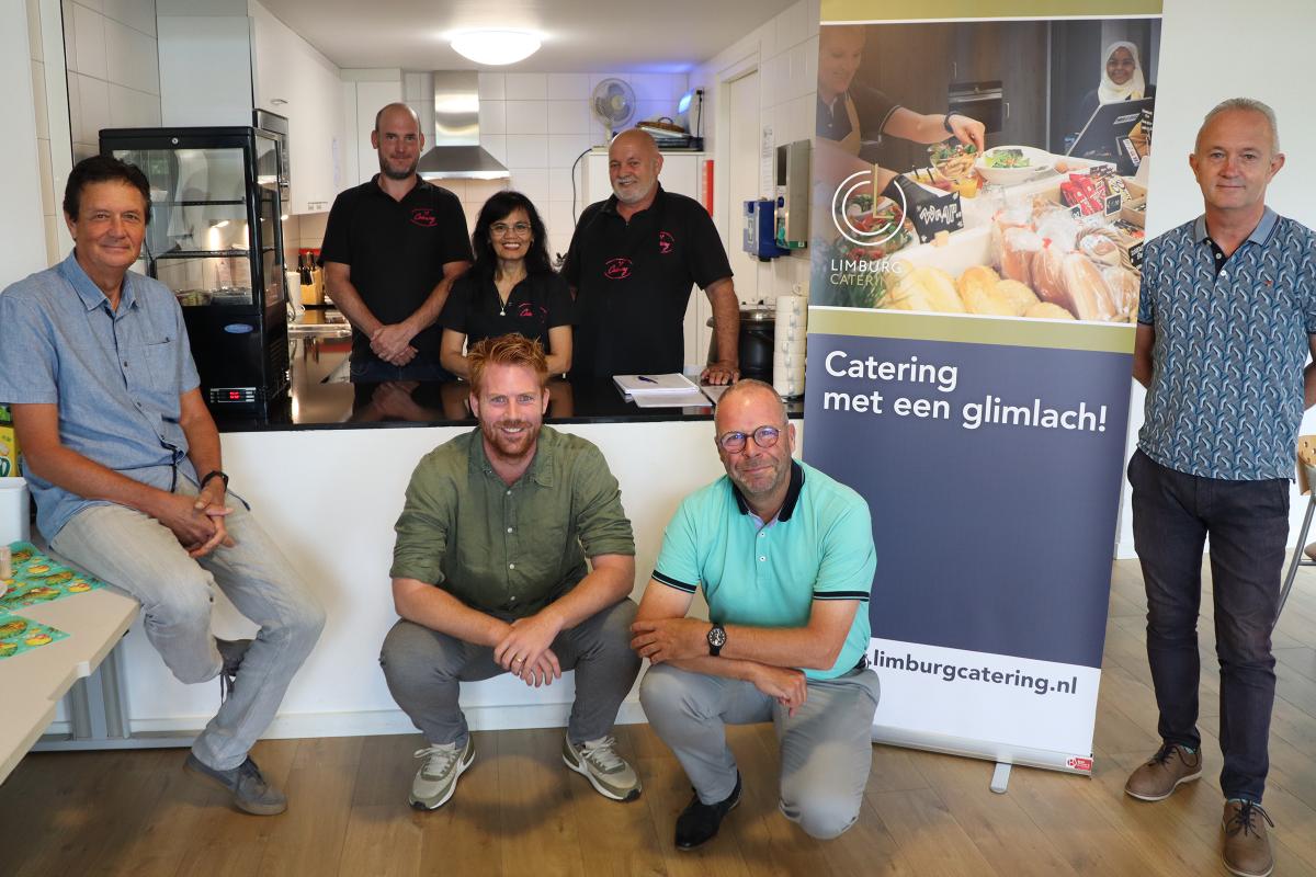 Groepsfoto van alle betrokkenen voor de counter in de kantine van MOB