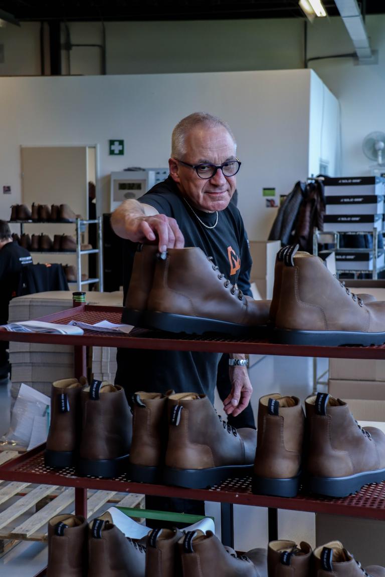 Medewerker Karel zet schoenen die klaar zijn op een rek